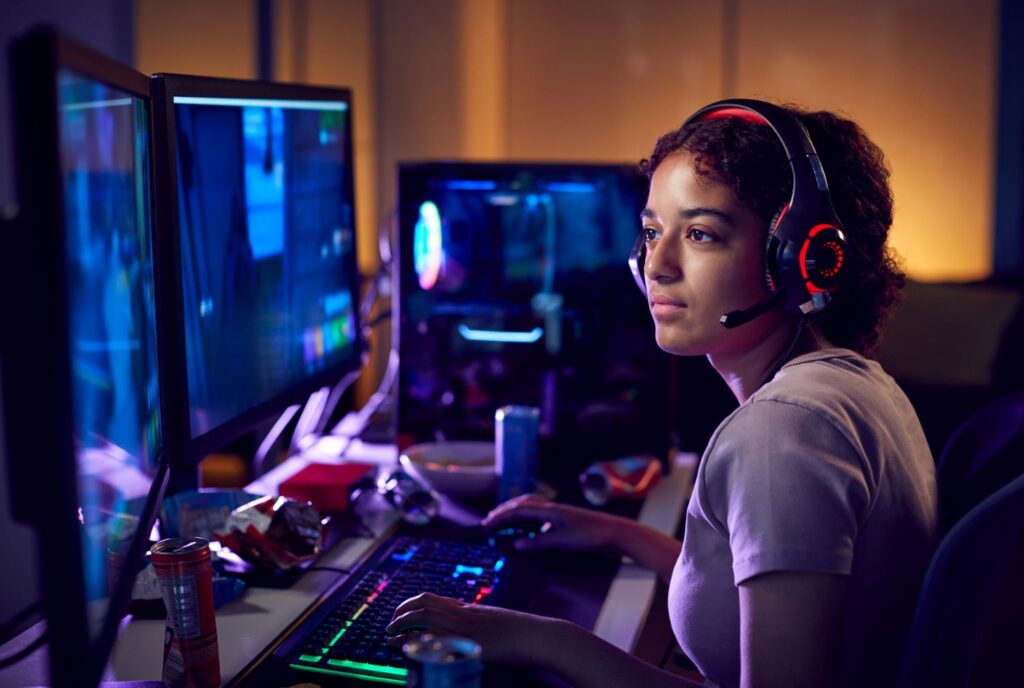 Young woman playing games on multiple monitors.